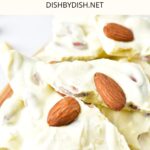 Up close view of almond white chocolate bark on wooden plate.