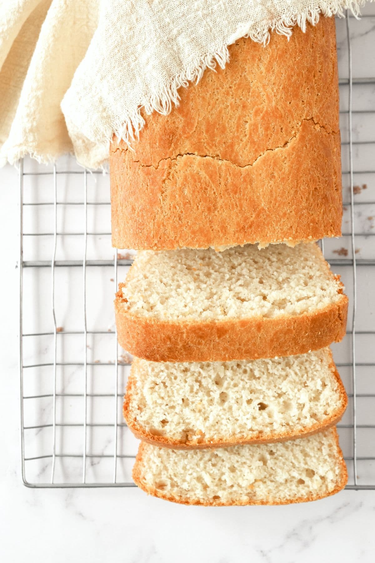 Half-sliced loaf of egg-free gluten-free bread on wire rack.
