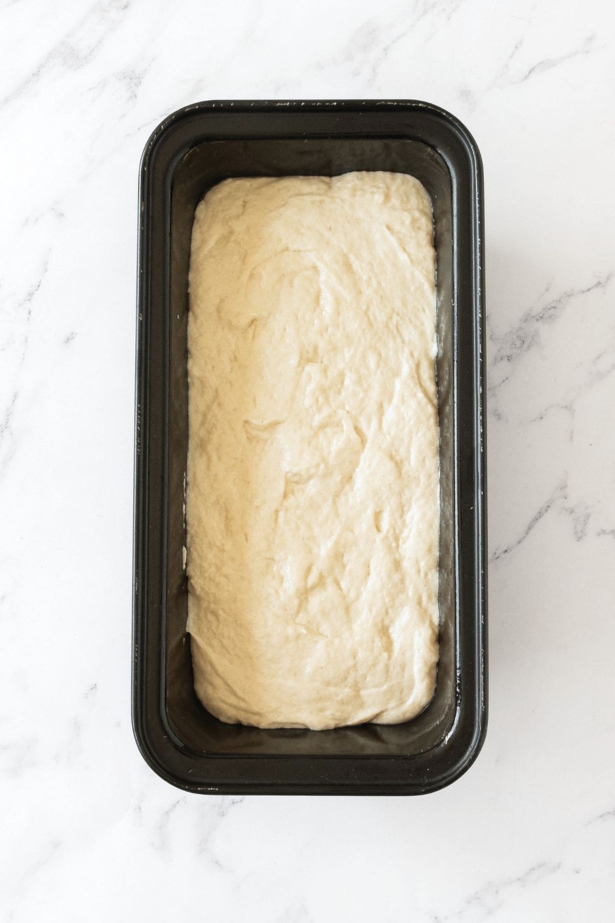 Bread dough in metal loaf pan.
