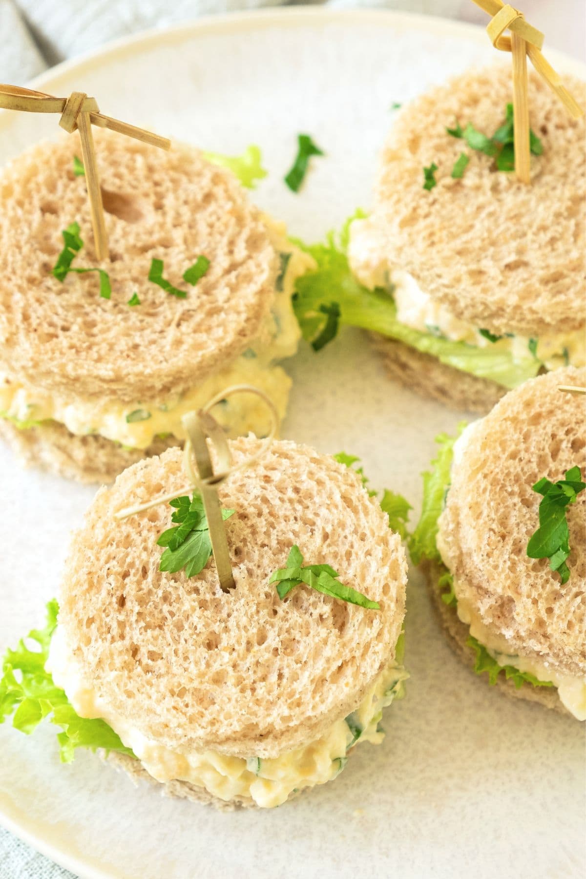 Egg salad tea sandwiches on plate.