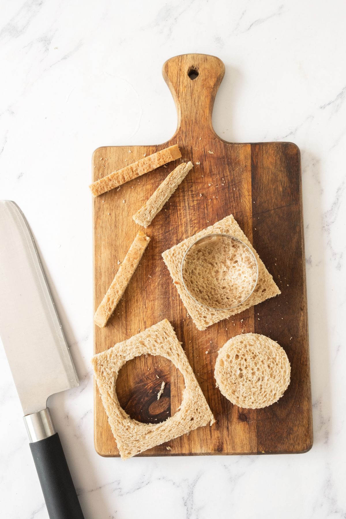 Using cookie cutter to cut circles from slices of bread.