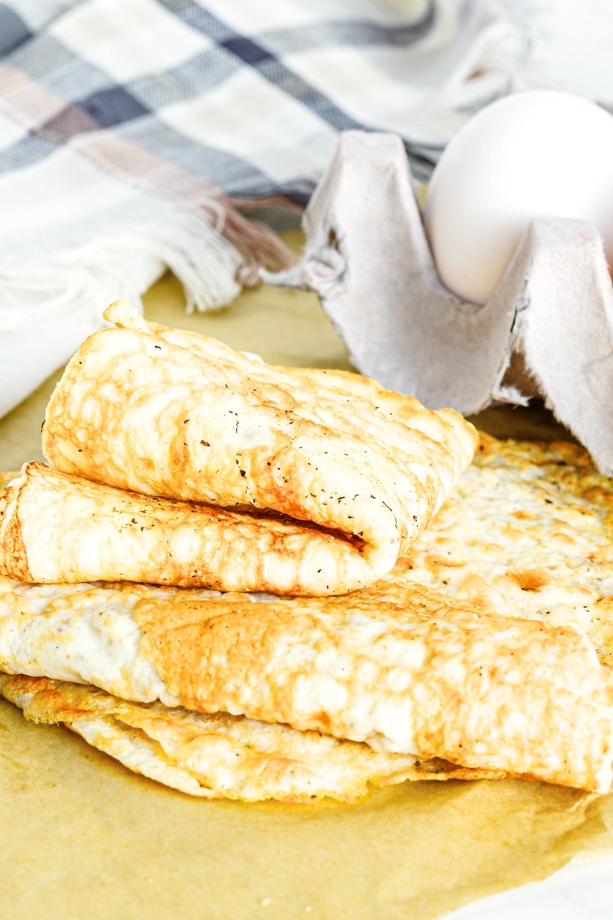 Folded egg white tortilla wraps on parchment paper.
