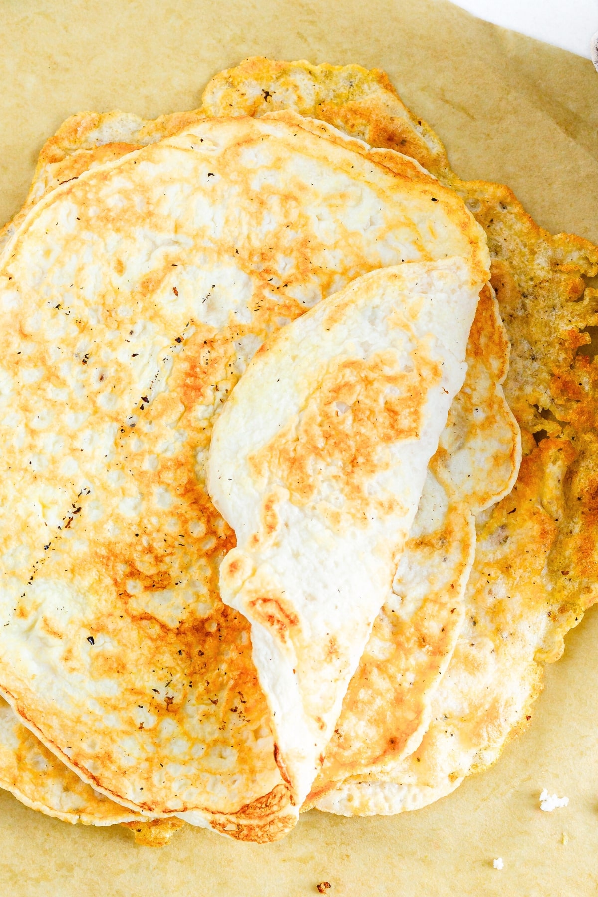Top down view of a stack of egg white tortillas on parchment paper.