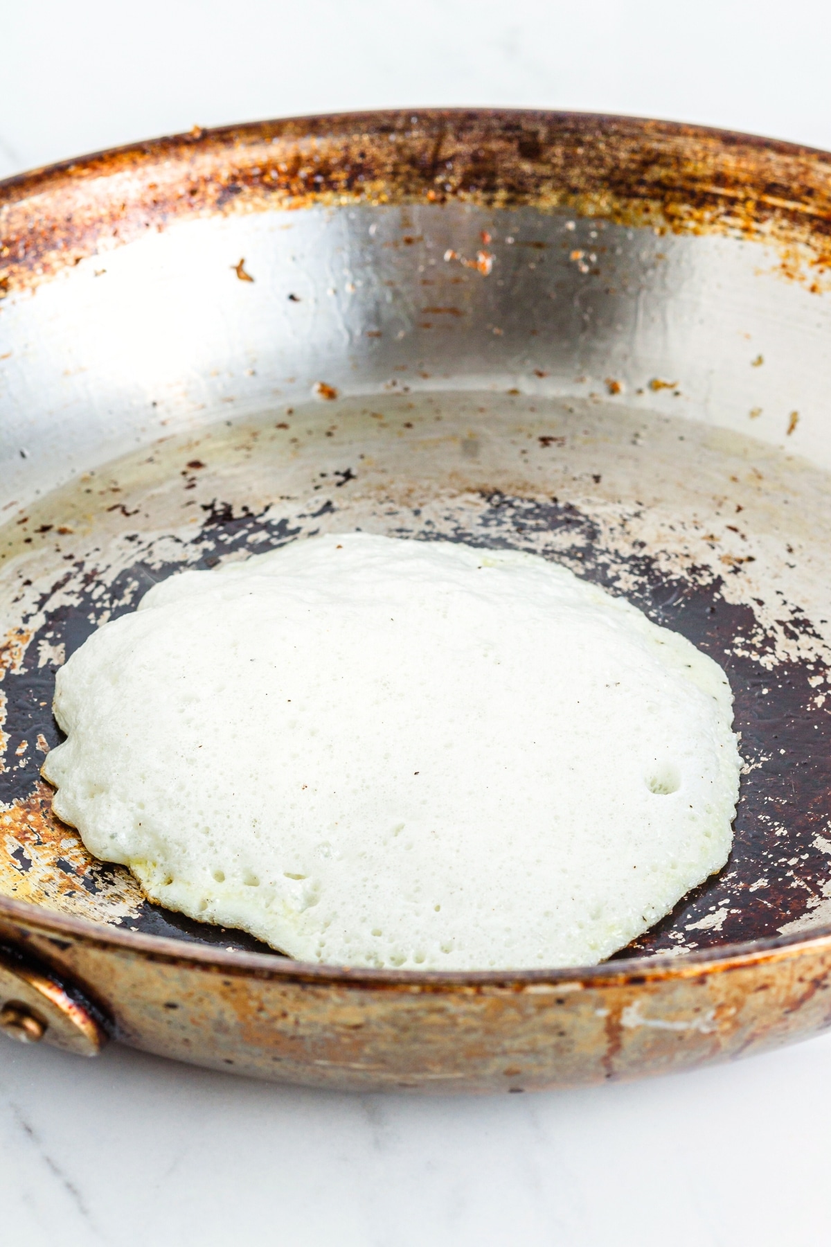 Cooking egg white tortilla in skillet.