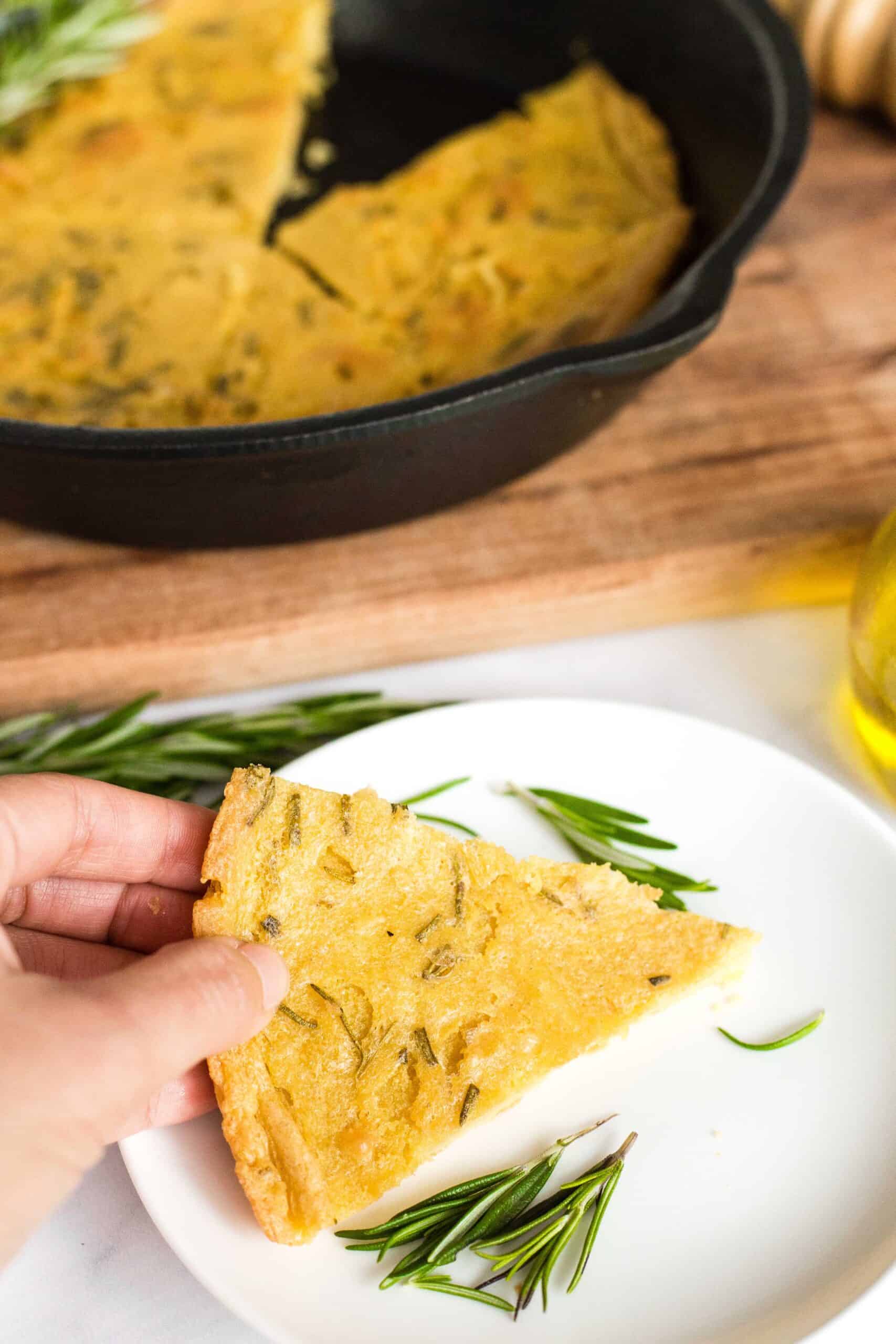 Holding a wedge of chickpea flatbread.
