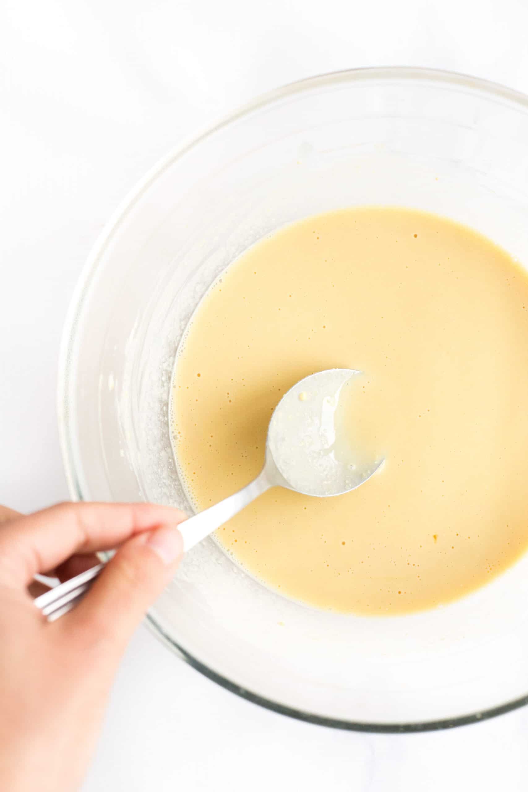 Dipping a spoon into a bowl of chickpea batter.