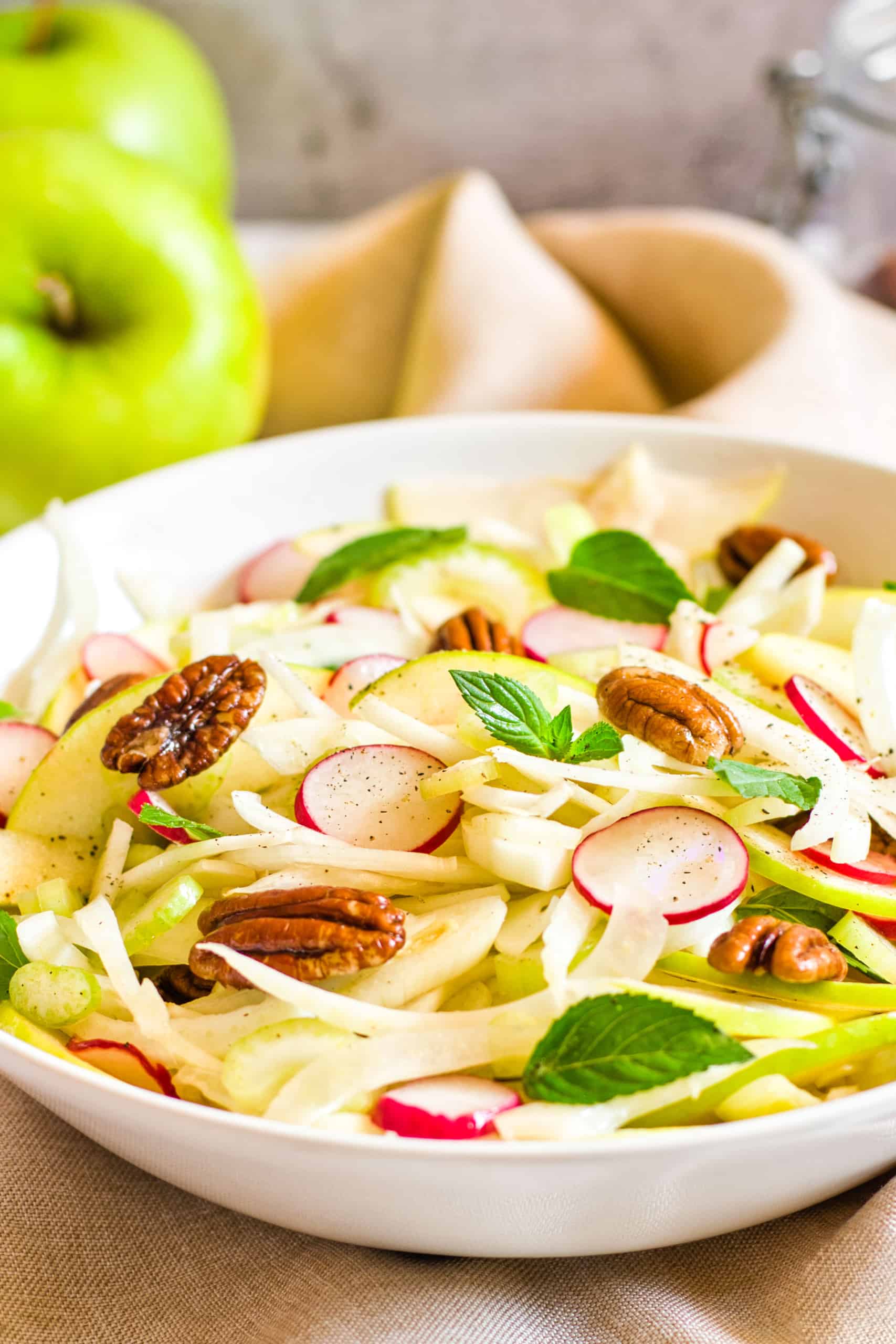 Fennel and apple salad in a white bowl.