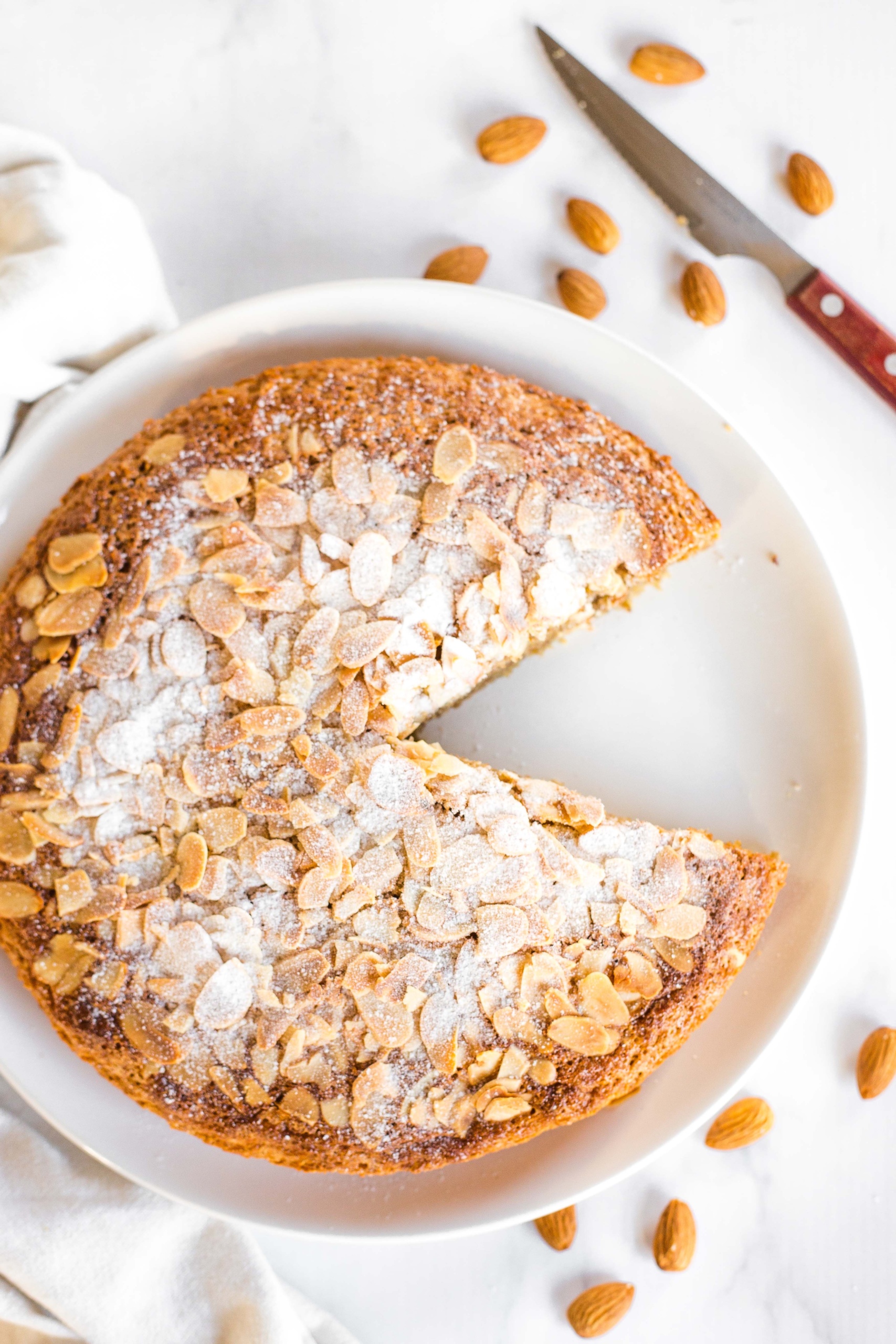 Amazing Flourless Lemon Almond Cake Recipe (Gluten-Free, Dairy-Free) Sliced flourless lemon almond cake on a round plate.