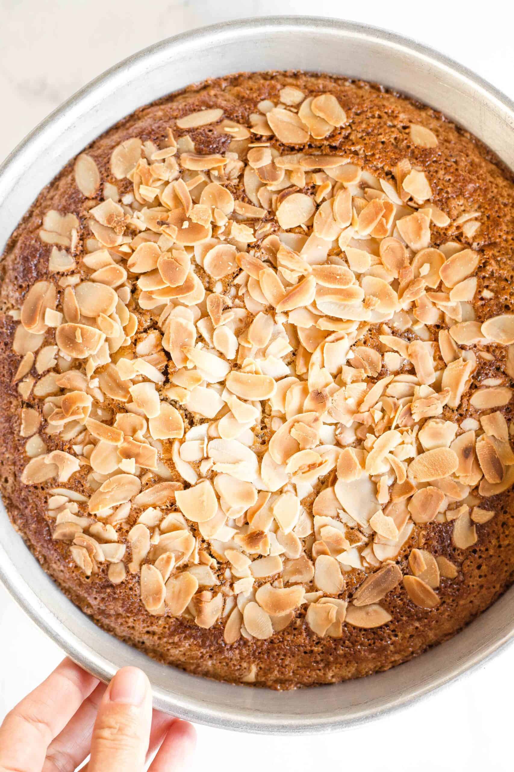 Hand reaching for freshly baked almond flour cake.