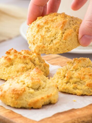 Holding up almond flour biscuit from wooden board.