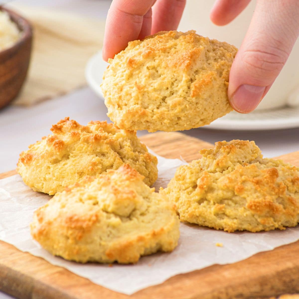 Holding up almond flour biscuit from wooden board.