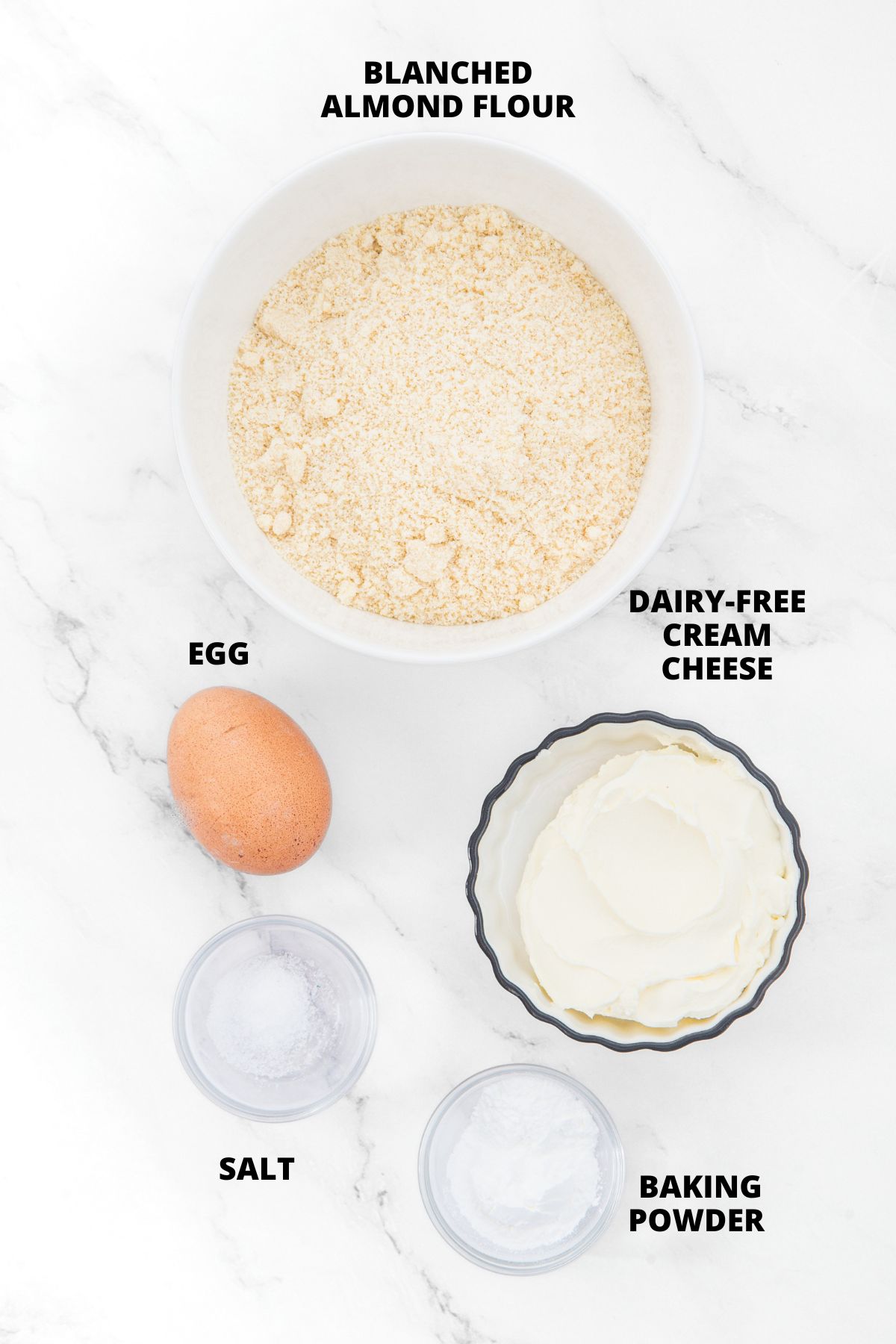 Top down view of ingredients for almond flour biscuits recipe laid out on marble board.