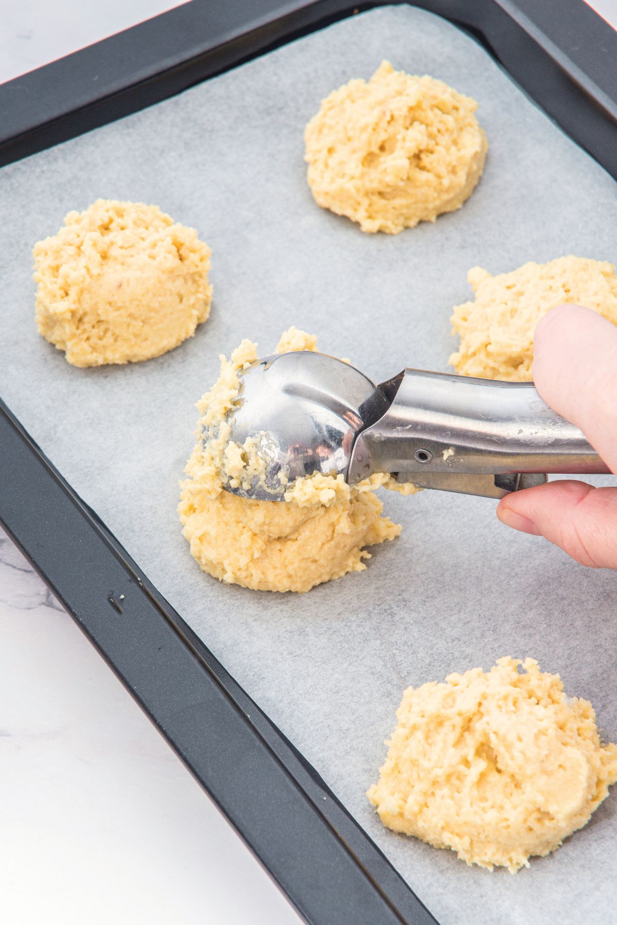 Scooping biscuit dough onto parchment-lined baking sheet