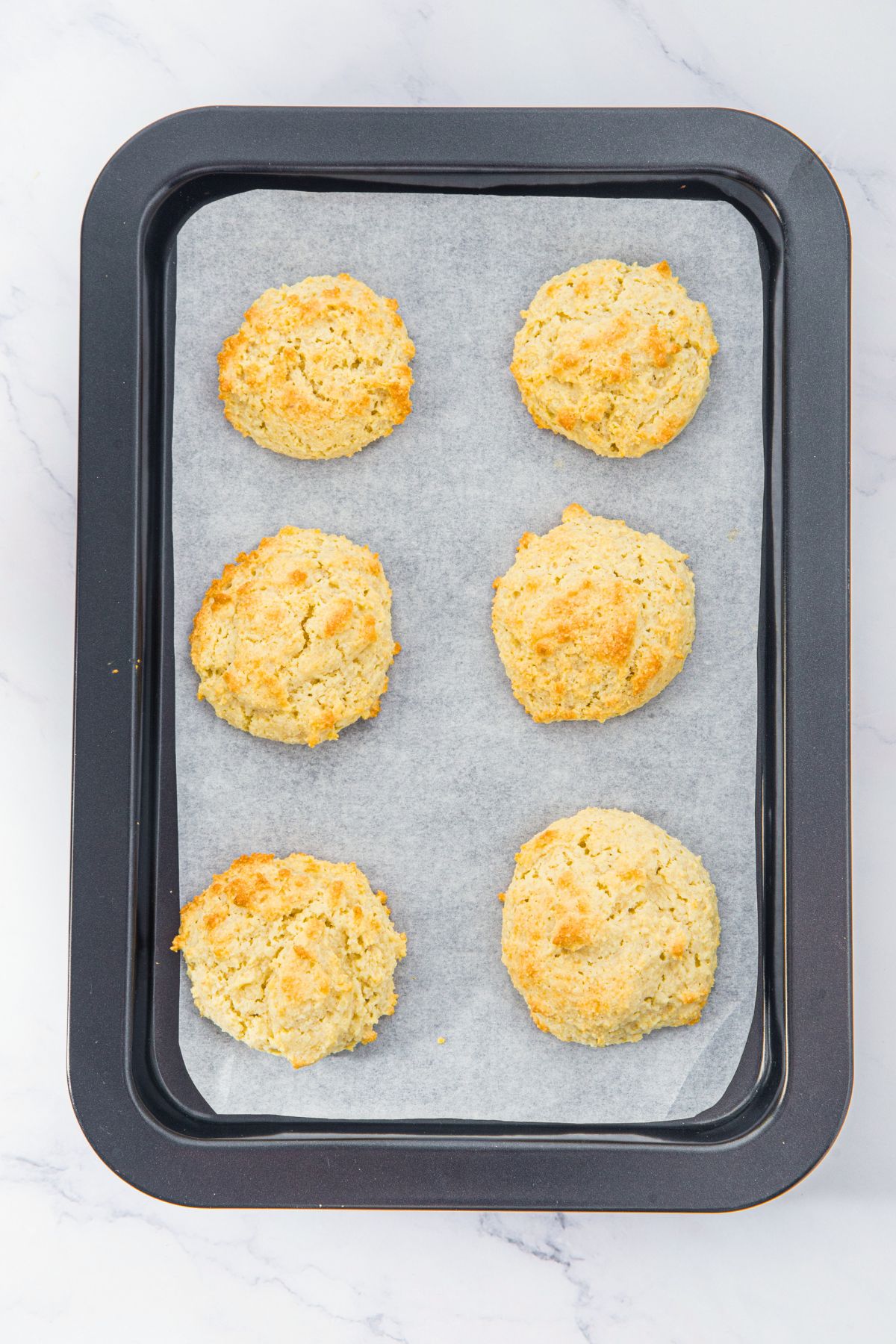 Freshly baked almond flour biscuits on parchment-lined baking sheet