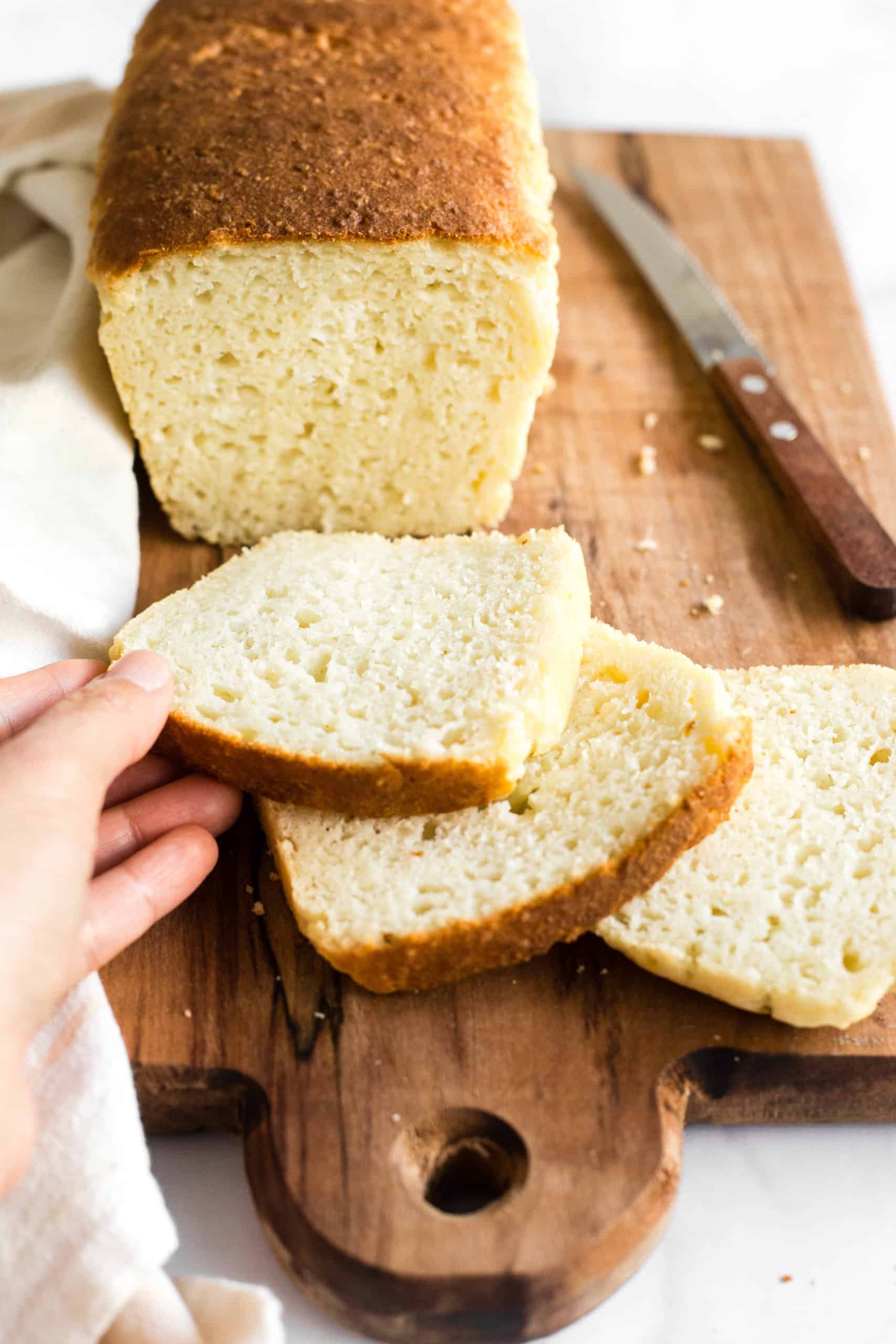 A hand holding a slice of freshly baked gluten-free bread.