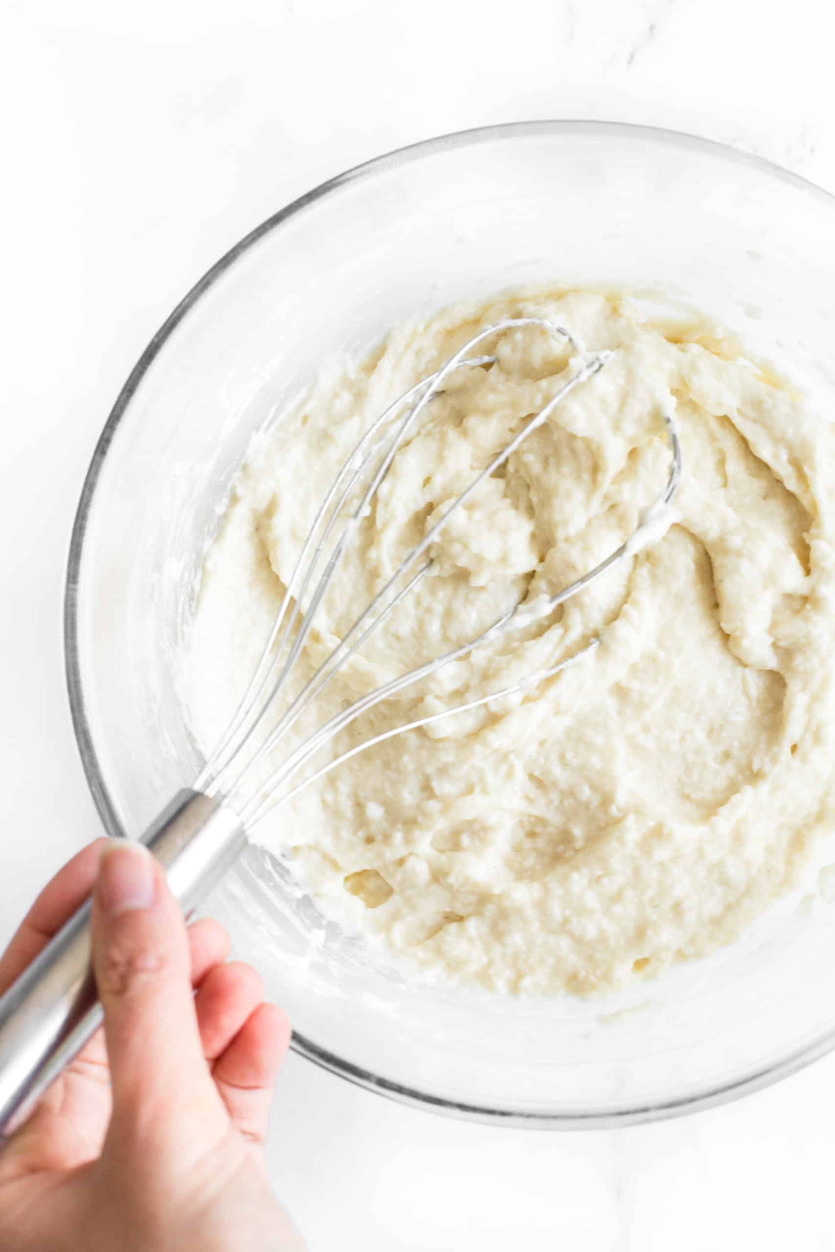 Gluten-free bread dough being mixed in a glass mixing bowl.