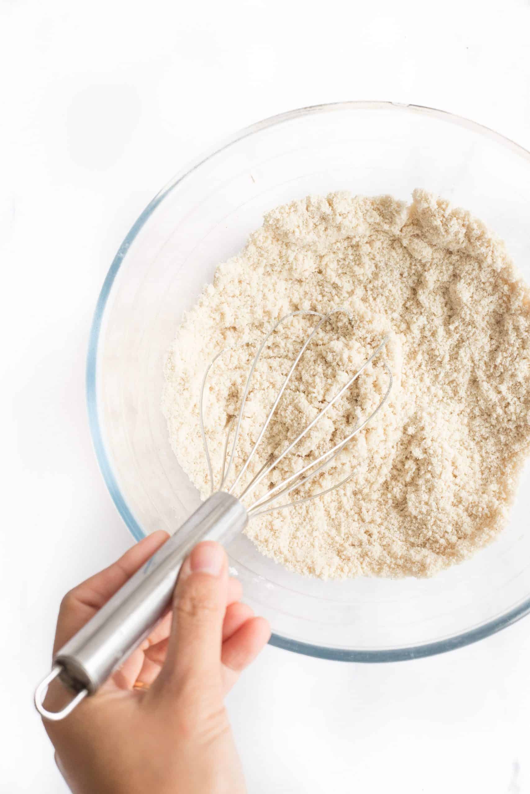 Whisking dry ingredients in a large glass bowl.