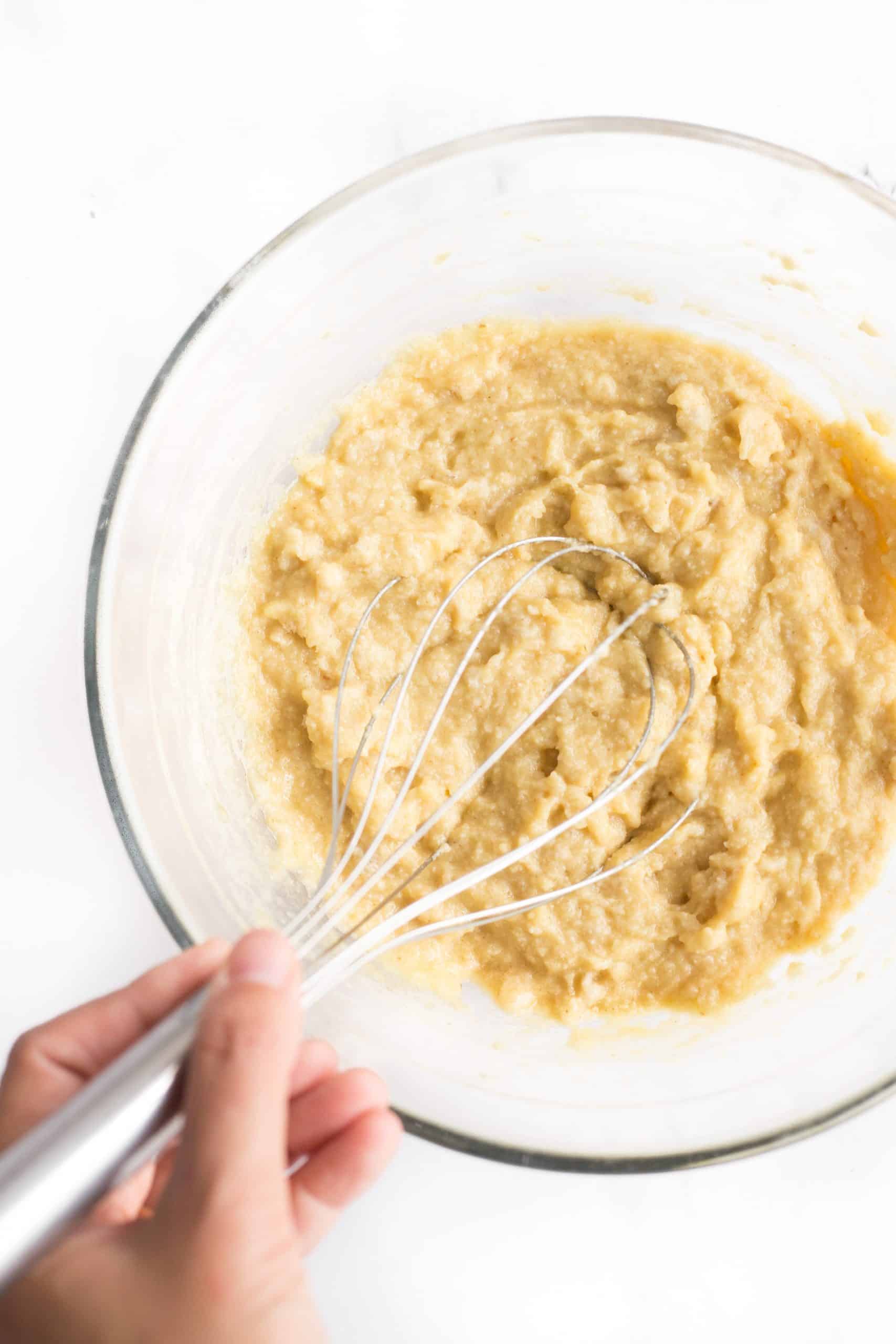 Hand mixing dough in a glass bowl.