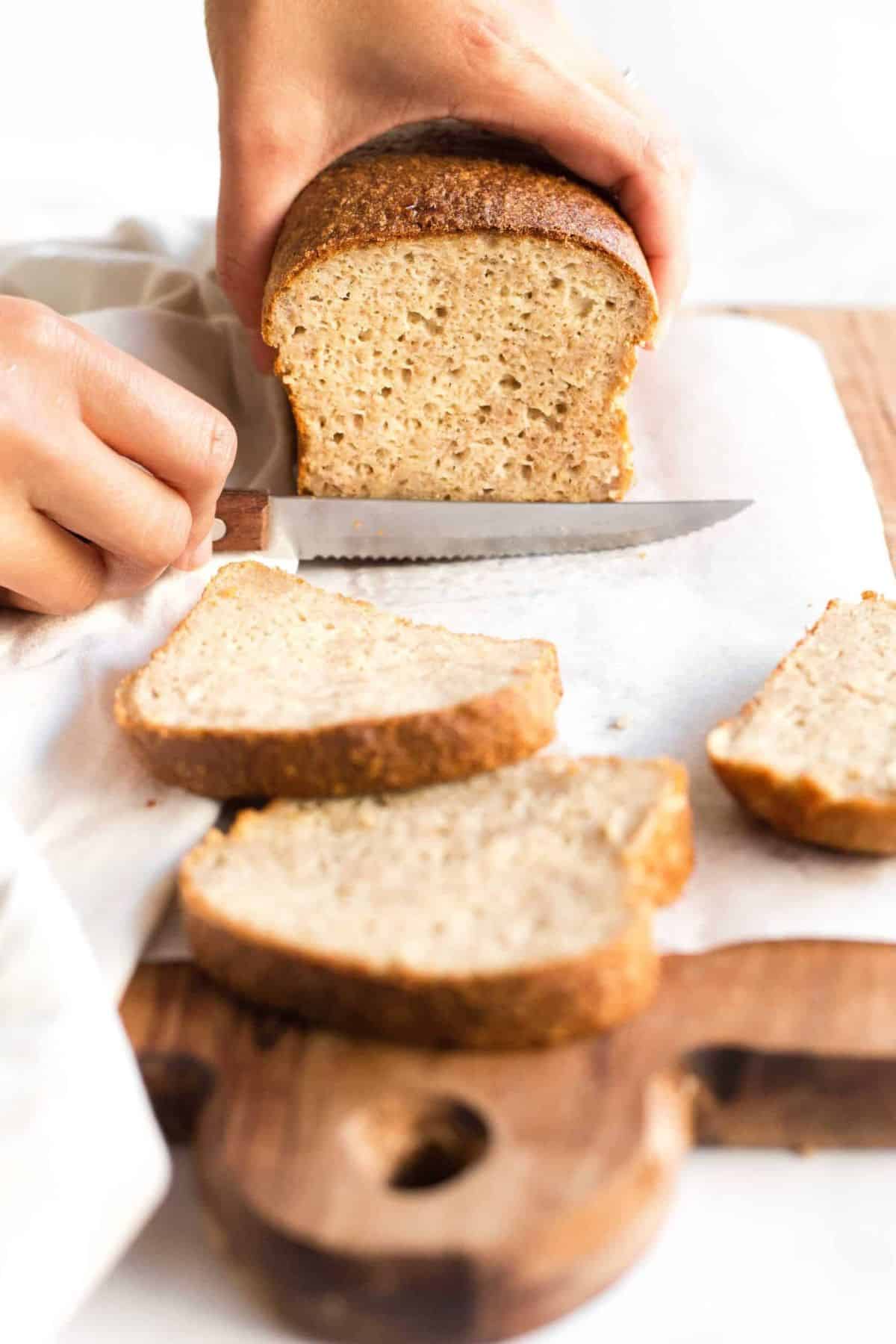 Slicing a loaf of gluten-free quinoa bread.