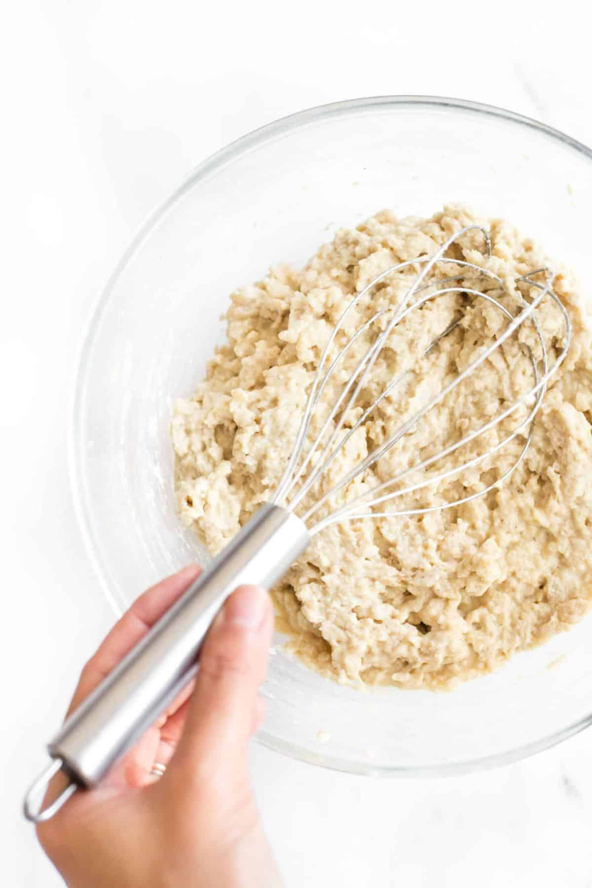 Mixing quinoa bread dough in glass bowl.