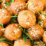 Top down view of fried potato balls sprinkled with grated parmesan.