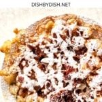 Top down view of funnel cake sprinkled with powdered sugar.