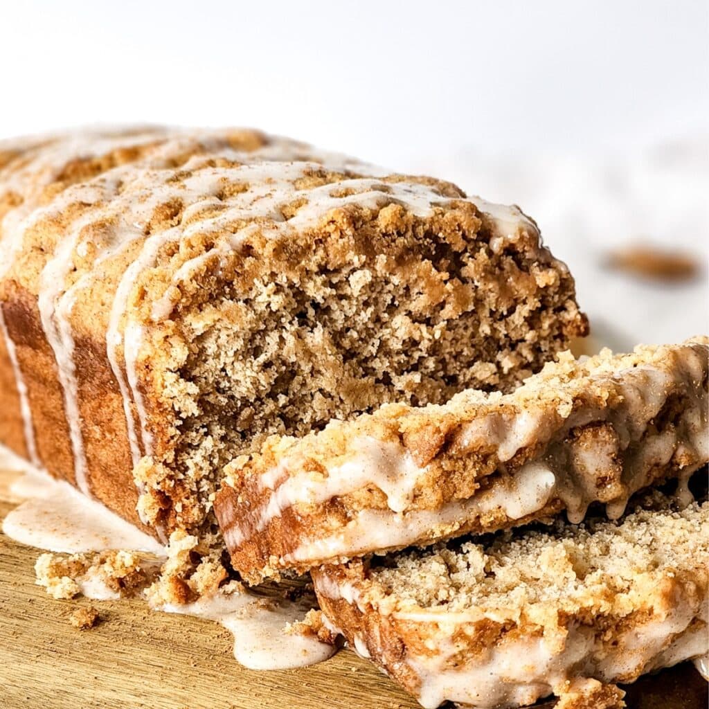 Half-sliced loaf of apple bread on wooden board.