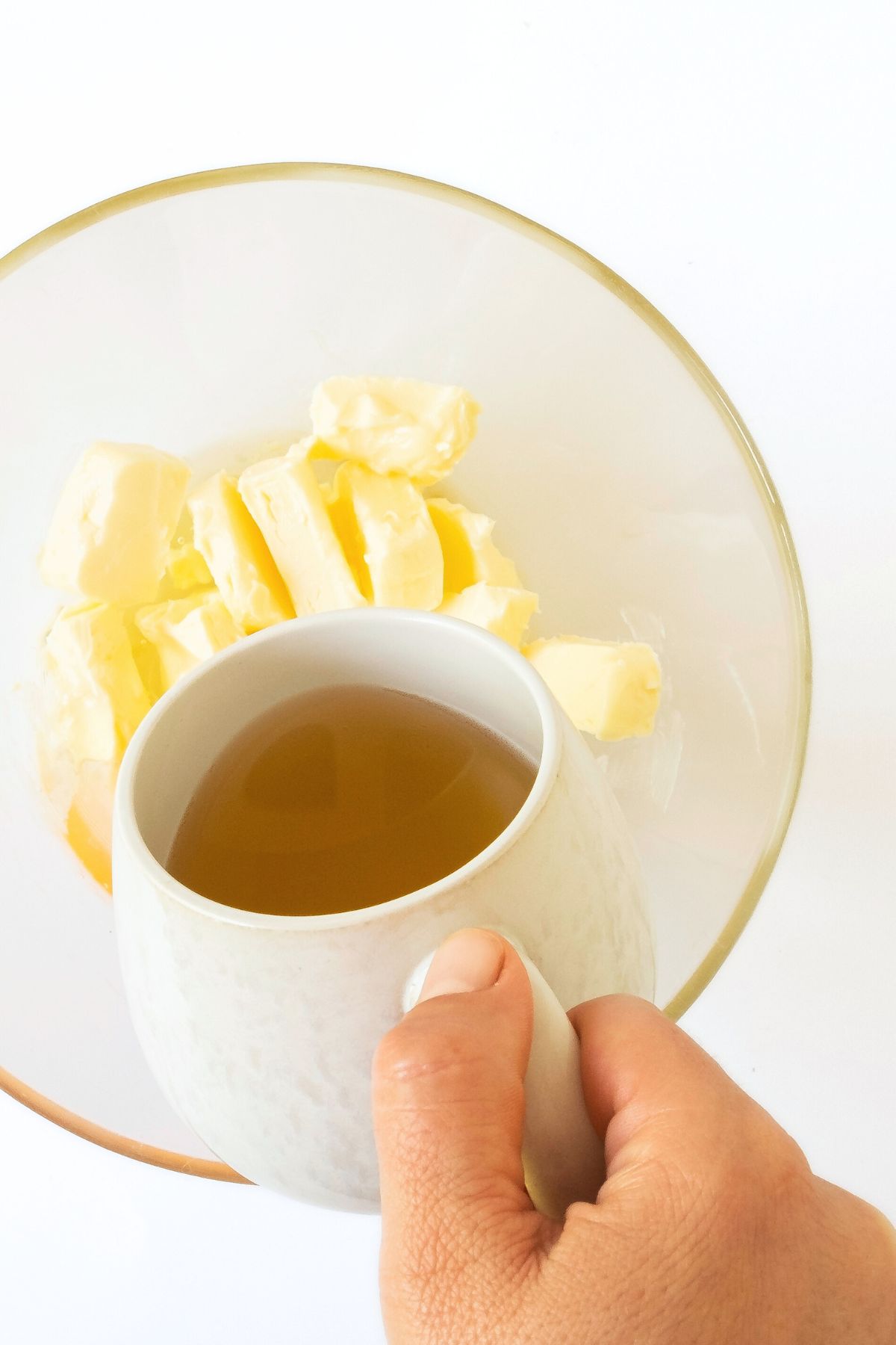 Pouring apple cider into a bowl of butter