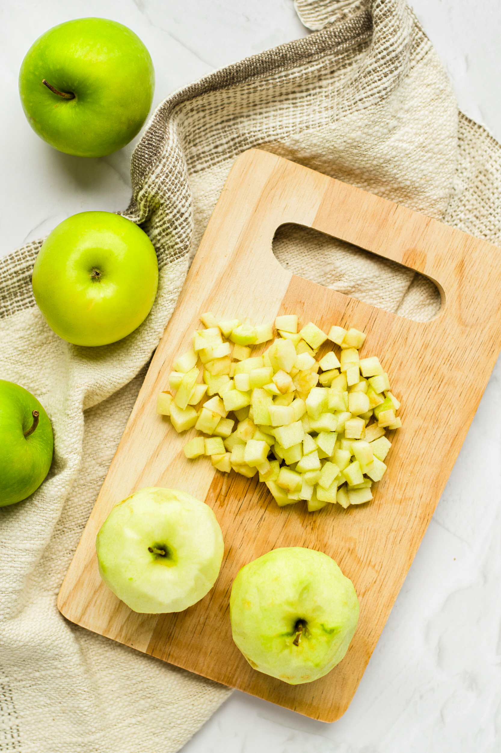 Cubed apples on wooden chopping board.