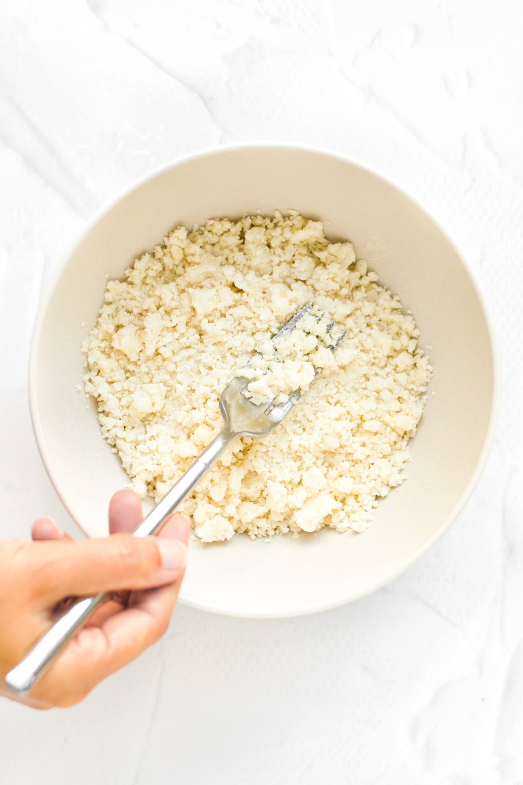 Pressing coconut oil into flour mixture to make crumble topping.