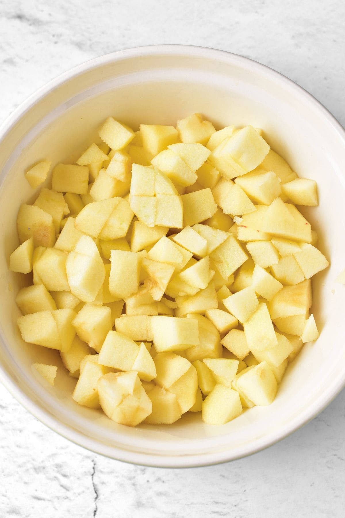 Cubed apples in a white bowl.