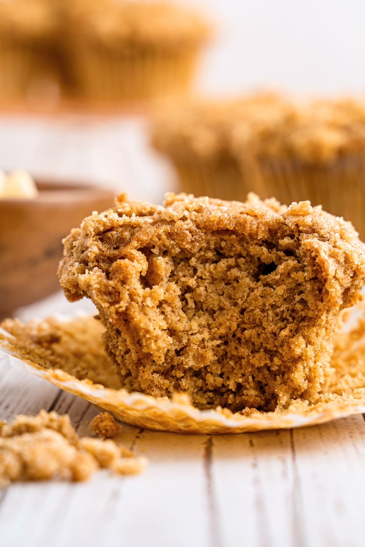 Half-eaten gluten-free applesauce muffin on paper liner.