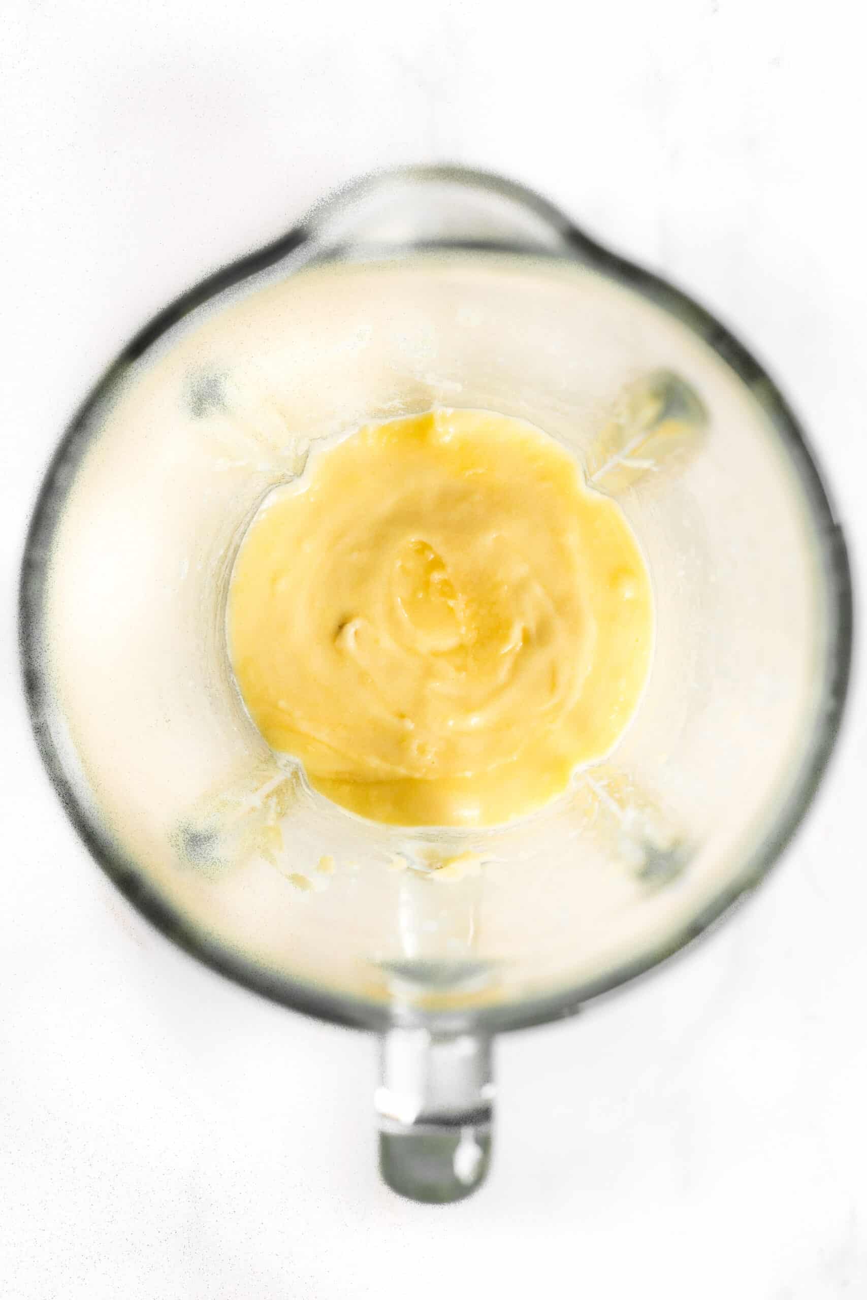 Yellow mixture in the bowl of a blender.