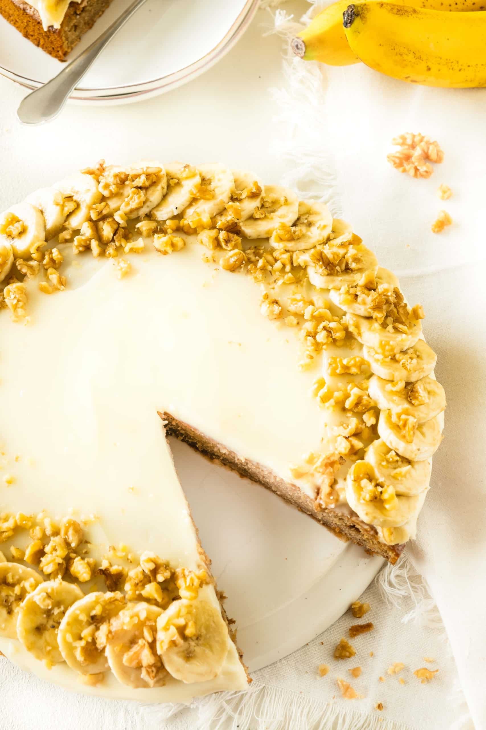 Half-sliced gluten-free banana cake on cake stand.