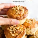 Hand reaching for a muffin on top of a stack of muffins.