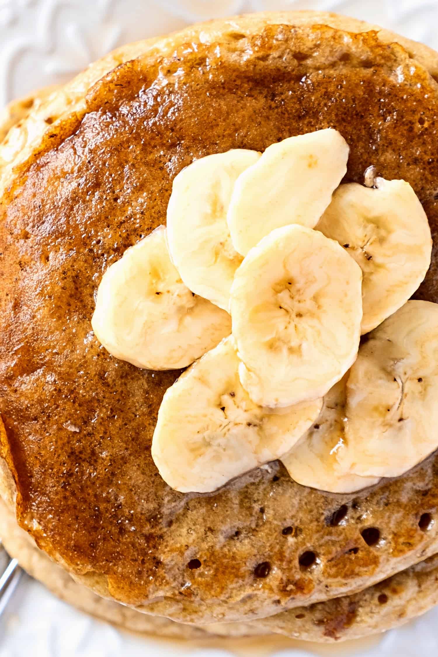 Top down view of sliced bananas on top of dairy-free banana pancakes.
