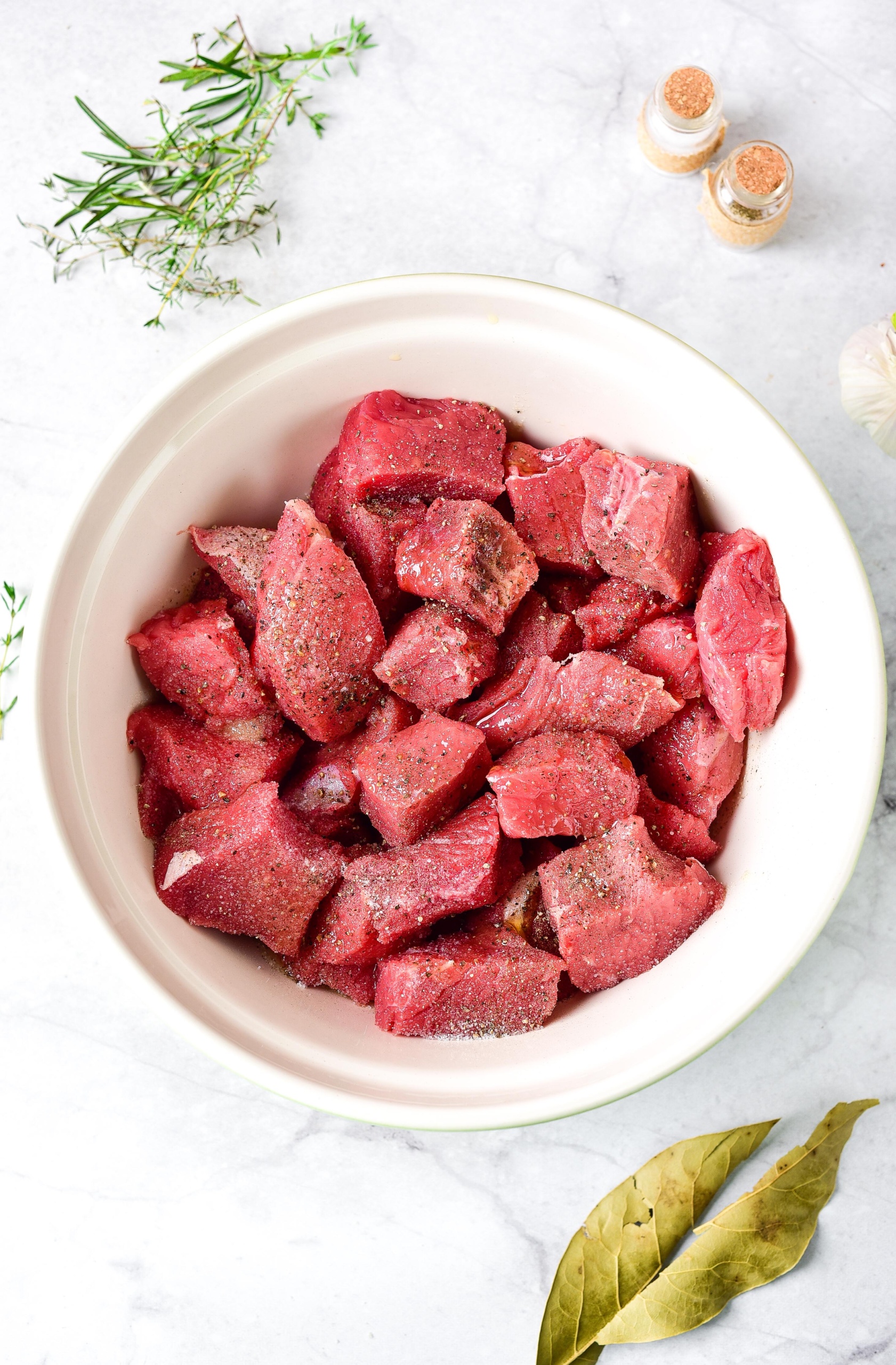Seasoned beef cubes in a white bowl.