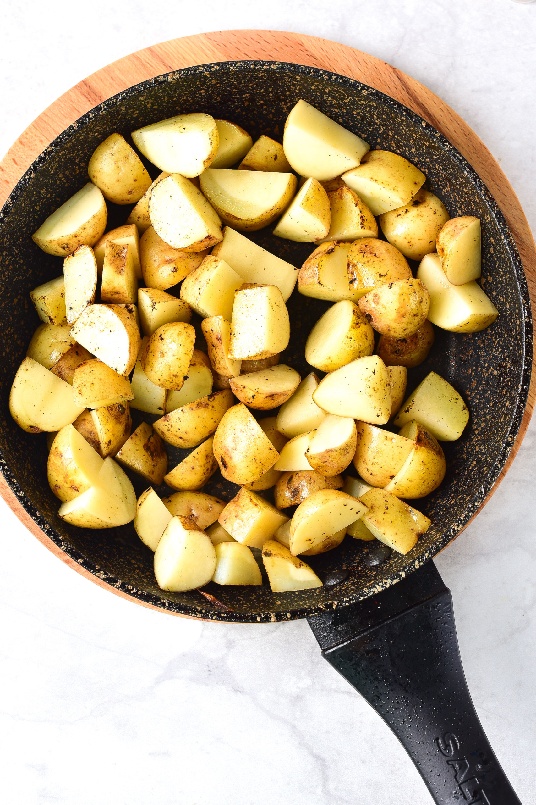 Baby potatoes cooking in skillet.