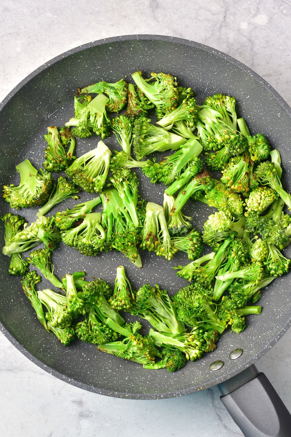 Sautéing broccoli florets in a skillet.