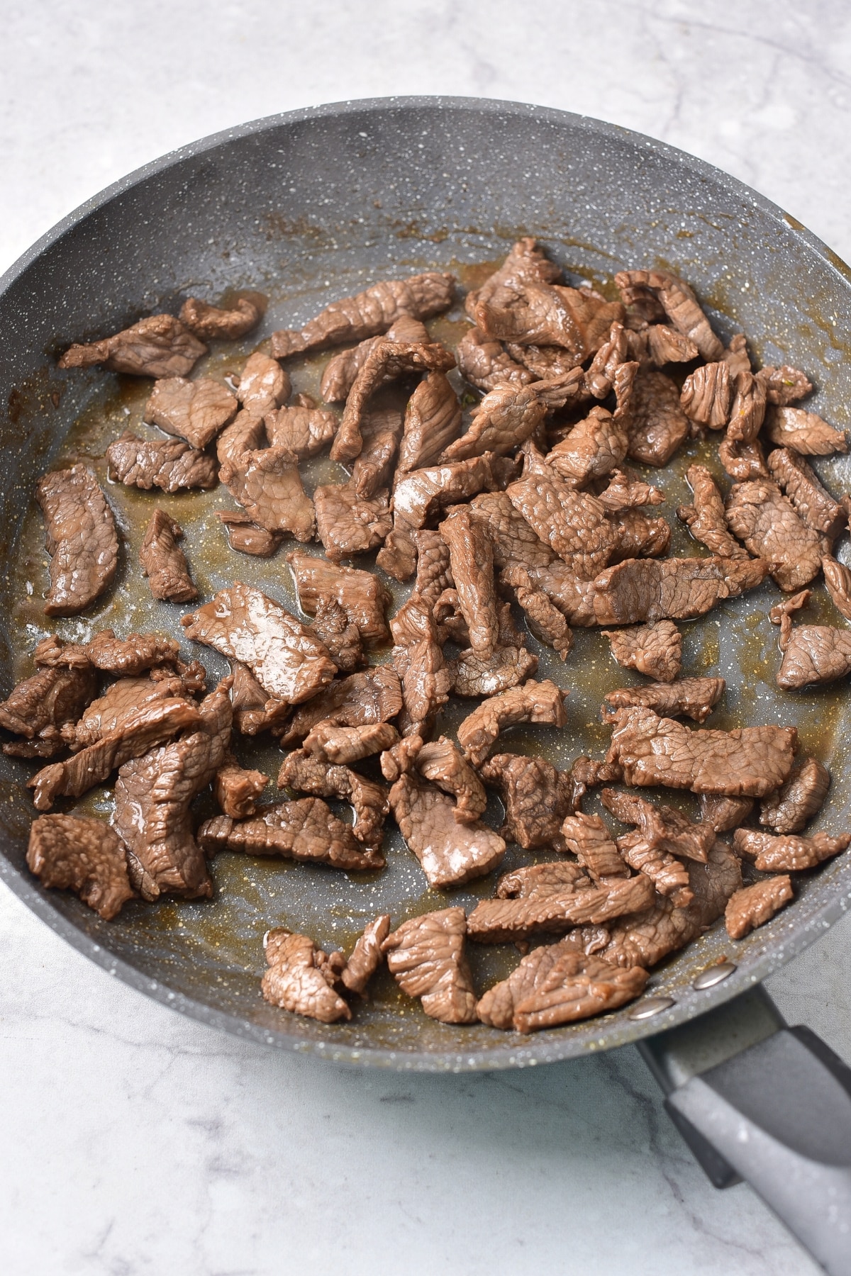 Stir frying beef slices in a skillet.