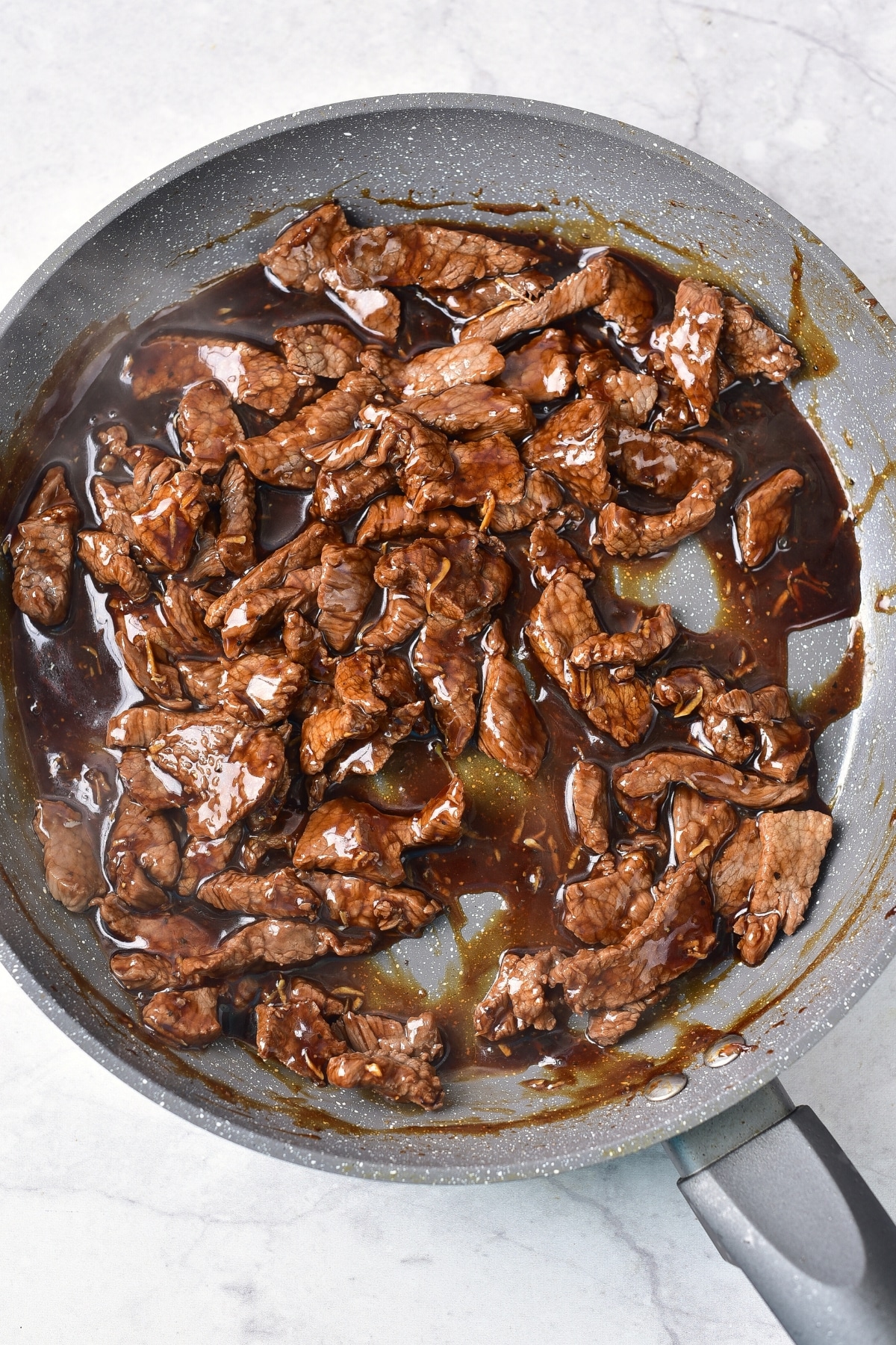 Cooking beef slices in skillet.