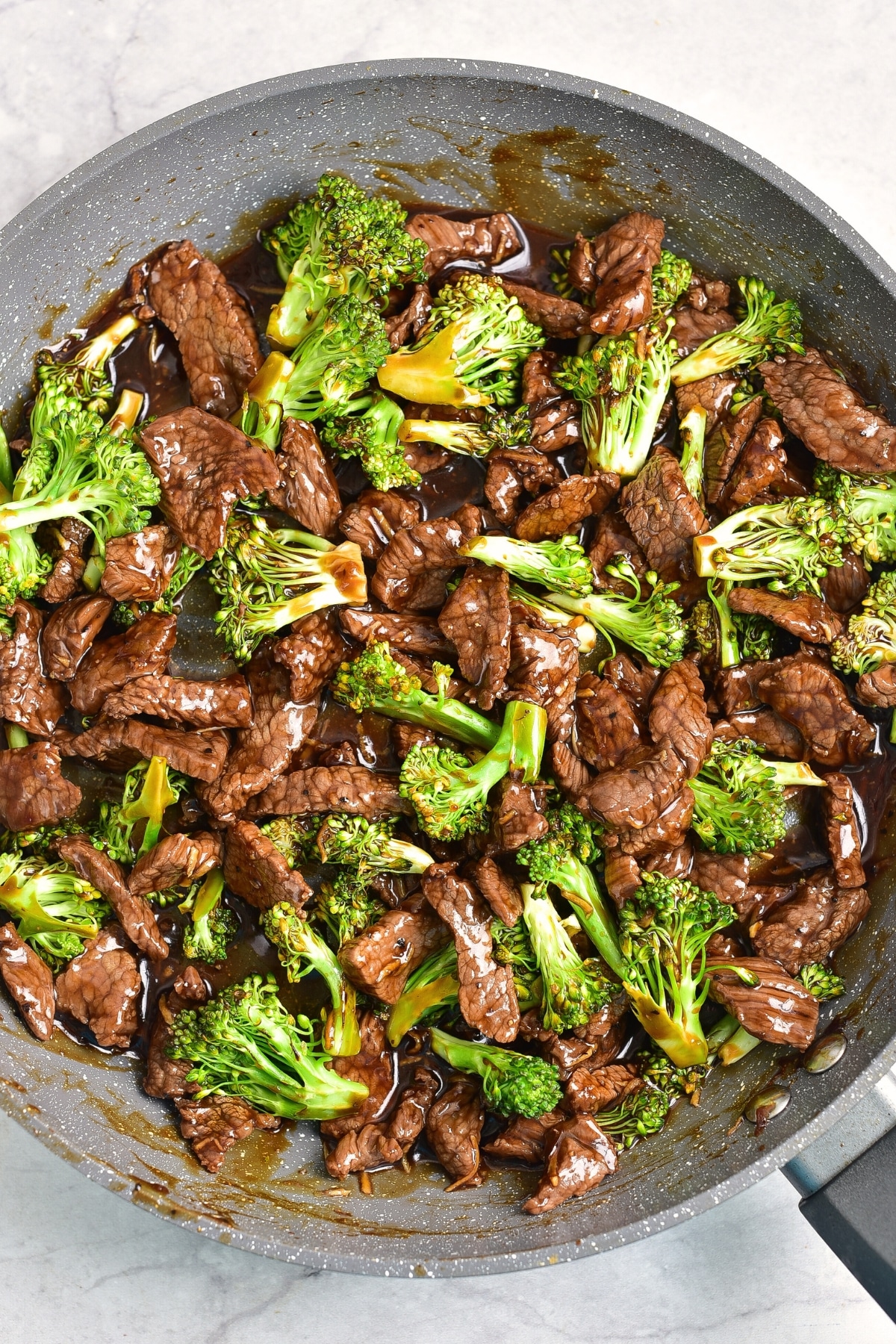 Sautéing broccoli florets and beef slices in a pan.