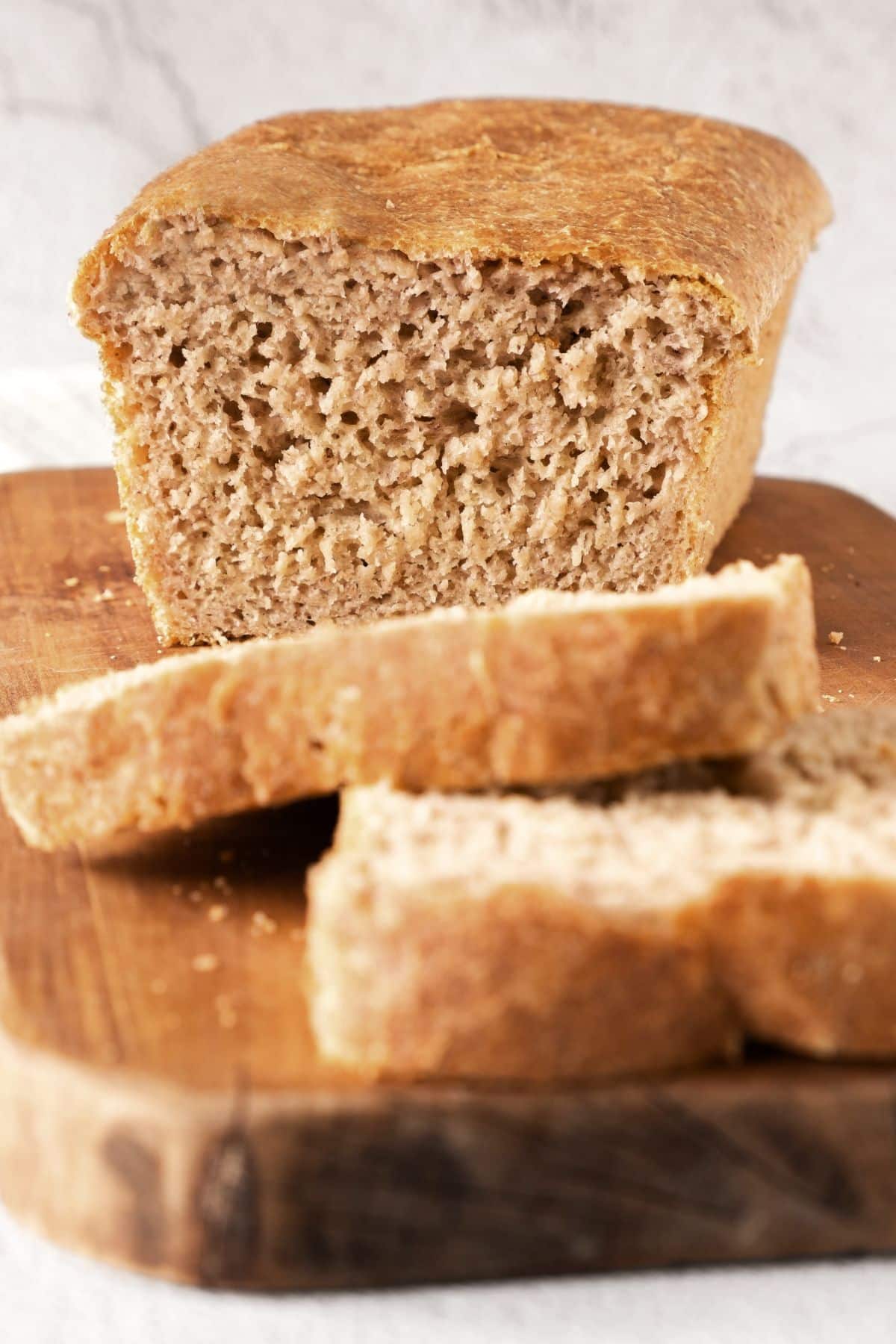 Up close shot of a half-sliced loaf of beer bread (gluten-free) on wooden board.