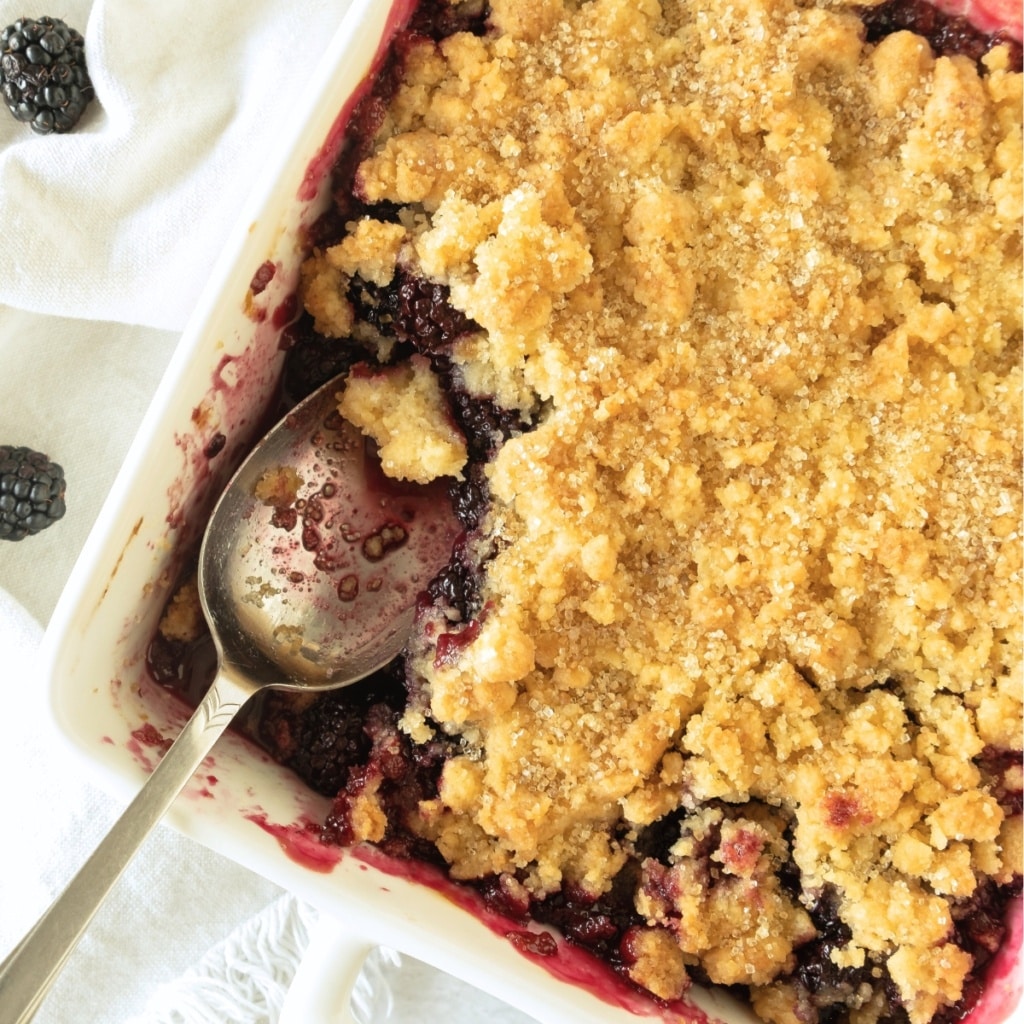 A spoon in half-eaten blackberry cobbler