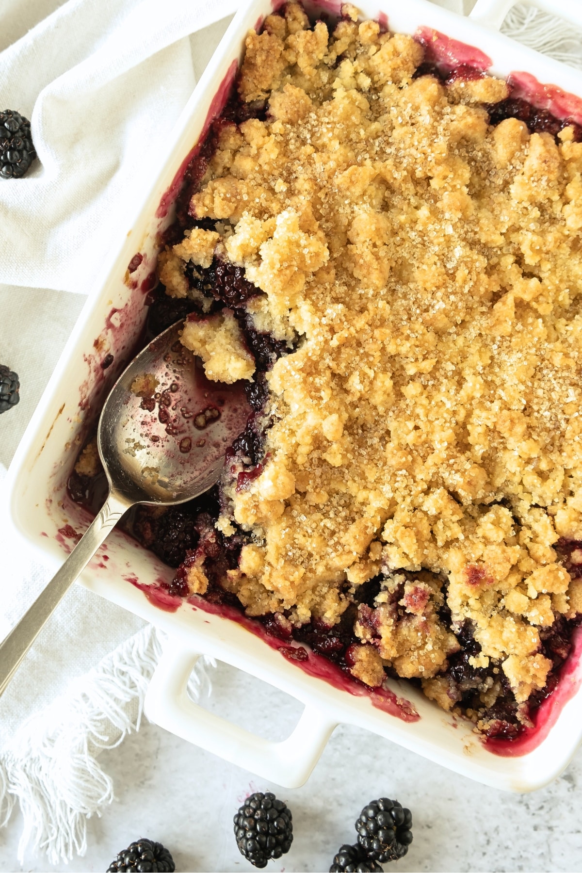 Top down view of half-eaten gluten-free blackberry cobbler surrounded with blackberries.