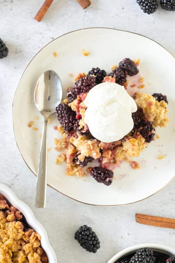 A bowl of gluten-free berry crisp topped with a scoop of dairy-free ice cream.