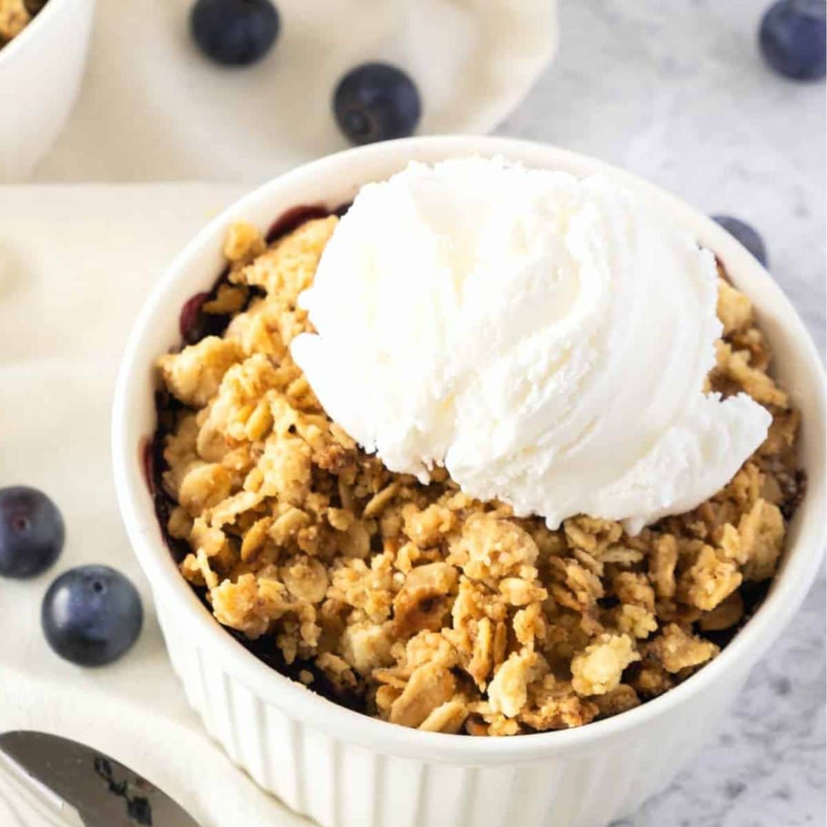 Gluten-free blueberry crisp topped with vanilla ice cream.