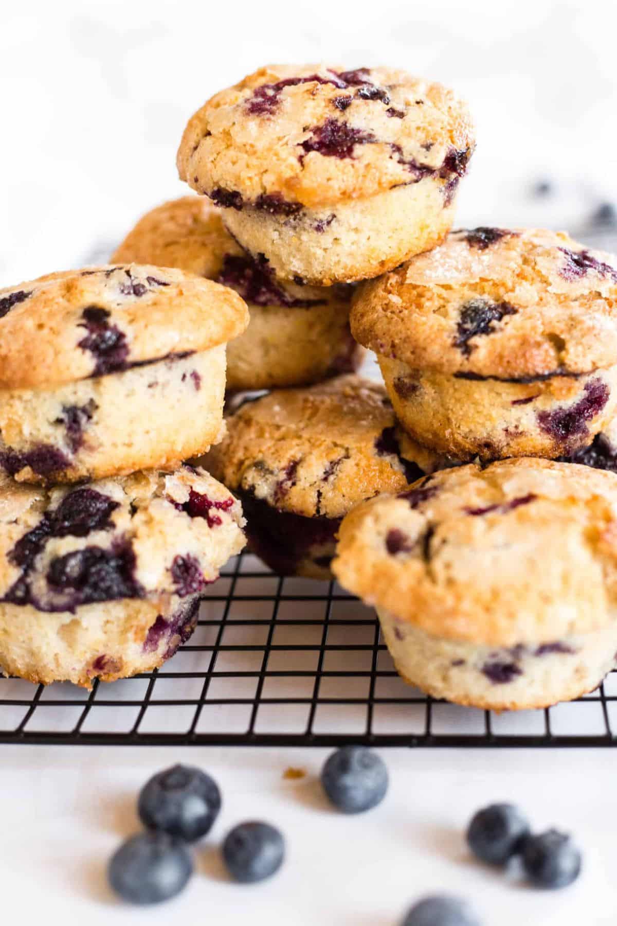 Gluten-free blueberry muffins stacked on wire rack.