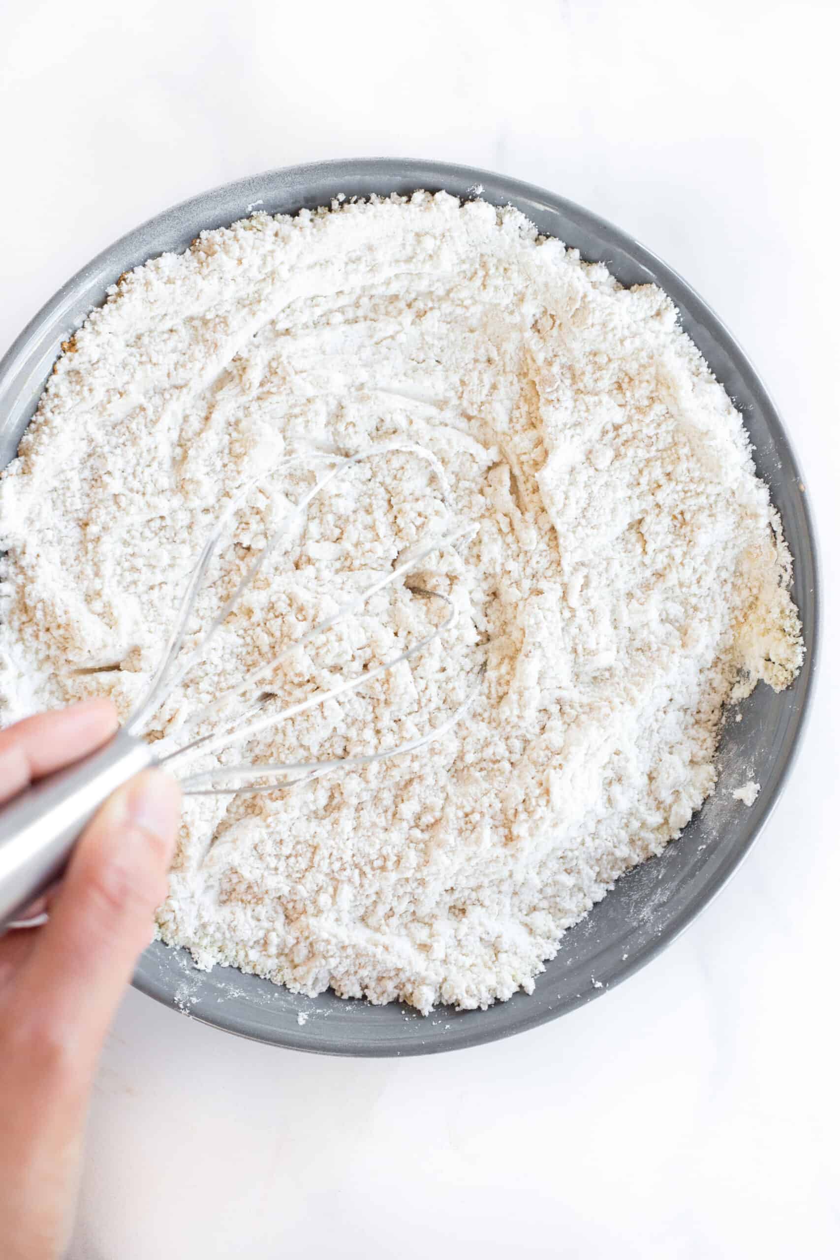 Whisking flour mixture in a grey bowl.