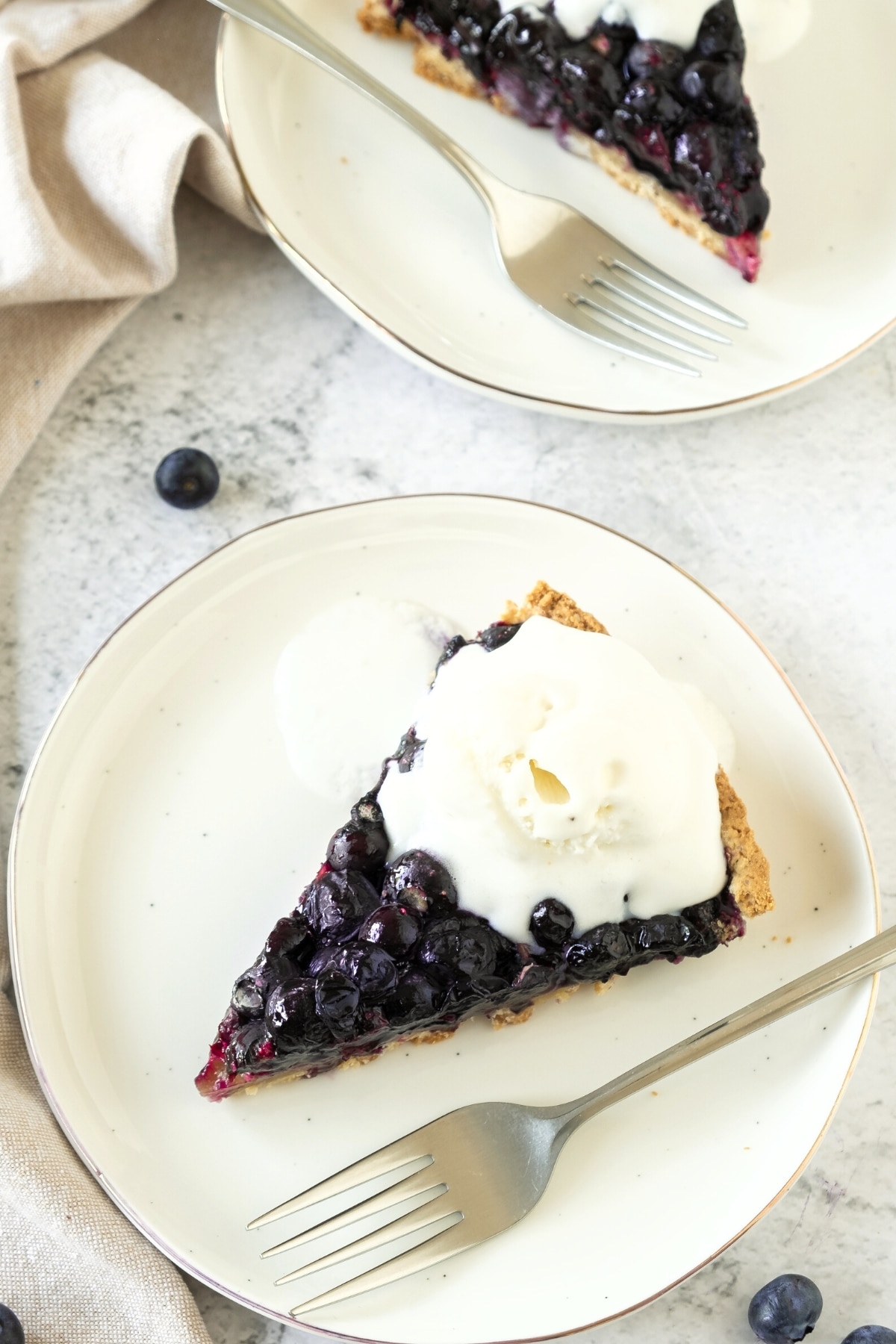GF blueberry pie and a fork on a white plate.